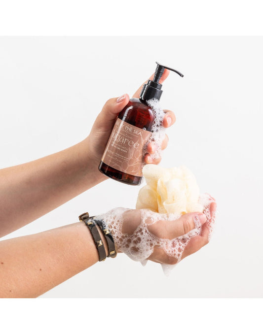 Product Image – Two hands, one holding a Sugaree pump bottle and the other a sudsy loofa