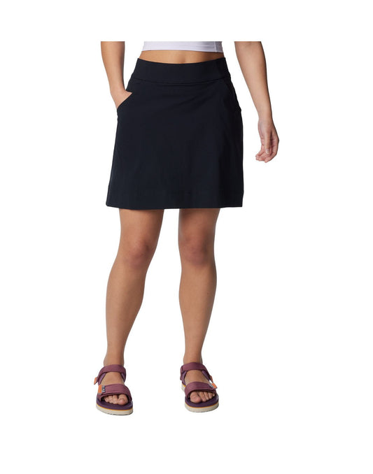 Product Image – Bottom half of woman wearing purple sandals and Columbia Women's Anytime™ Straight Skort in black with one hand in pocket, front view