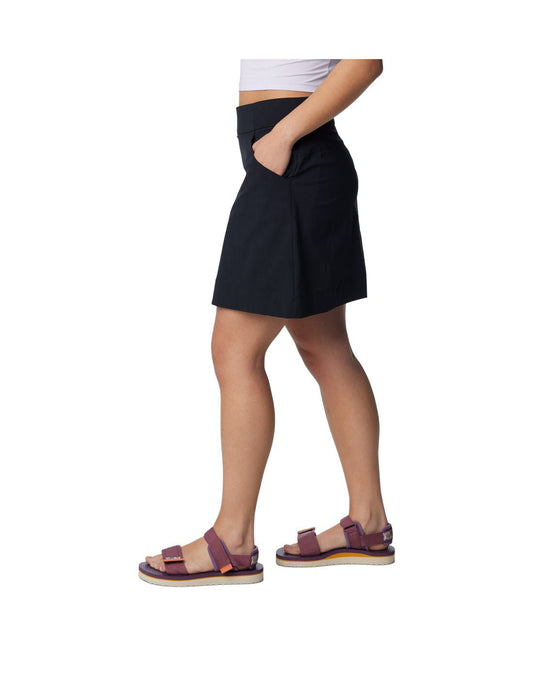 Product Image – Bottom half of woman wearing purple sandals and Columbia Women's Anytime™ Straight Skort in black with one hand in pocket, side view