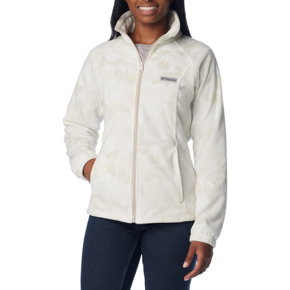 Woman wearing dark blue jeans and Columbia Women's Benton Springs™ Printed Full Zip Fleece Jacket in dark stone peonies, white with light beige floral pattern, front view, zipped up with one hand in pocket