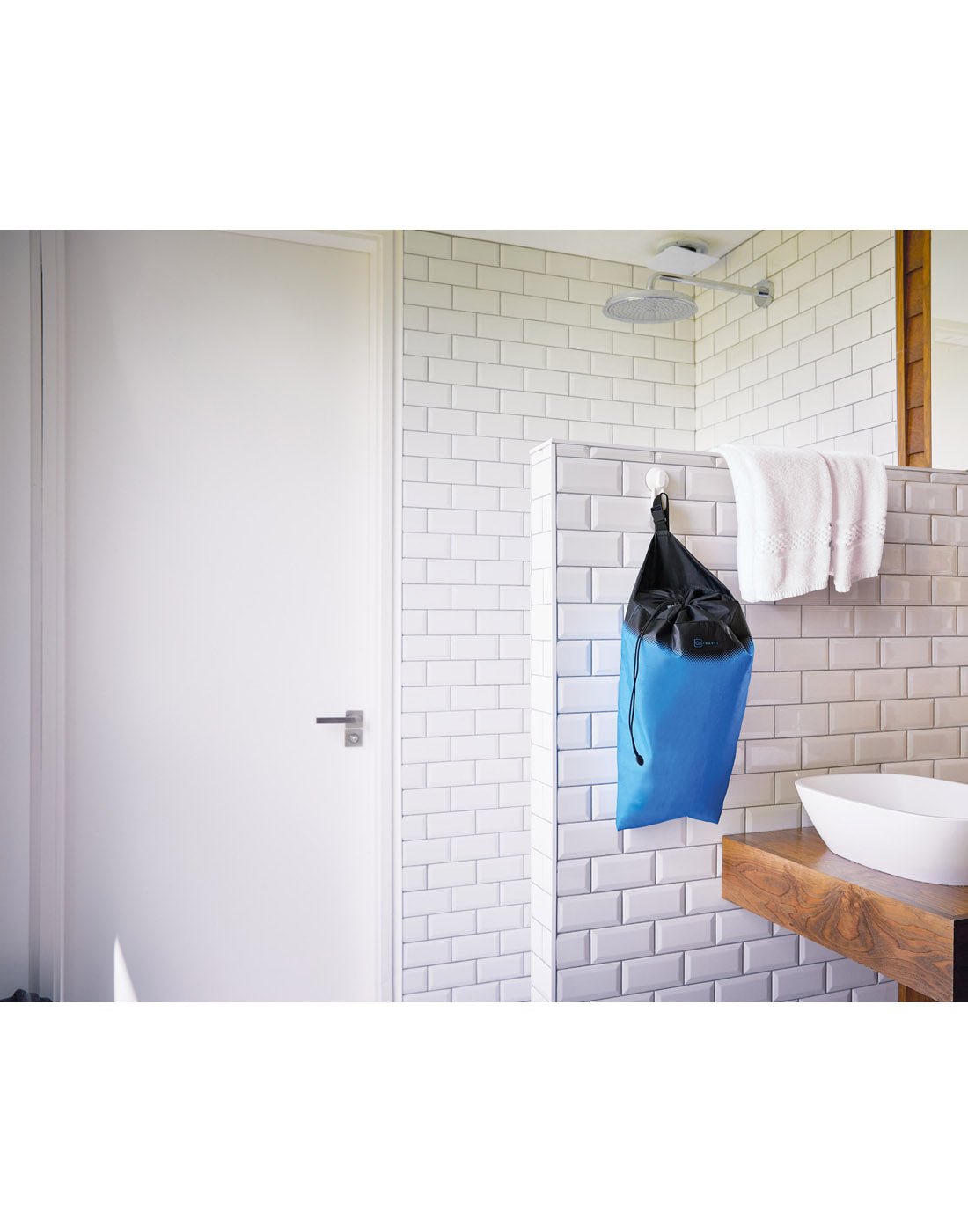 Lifestyle image of blue Go Travel Laundry Bag placed on a hook in a washroom.