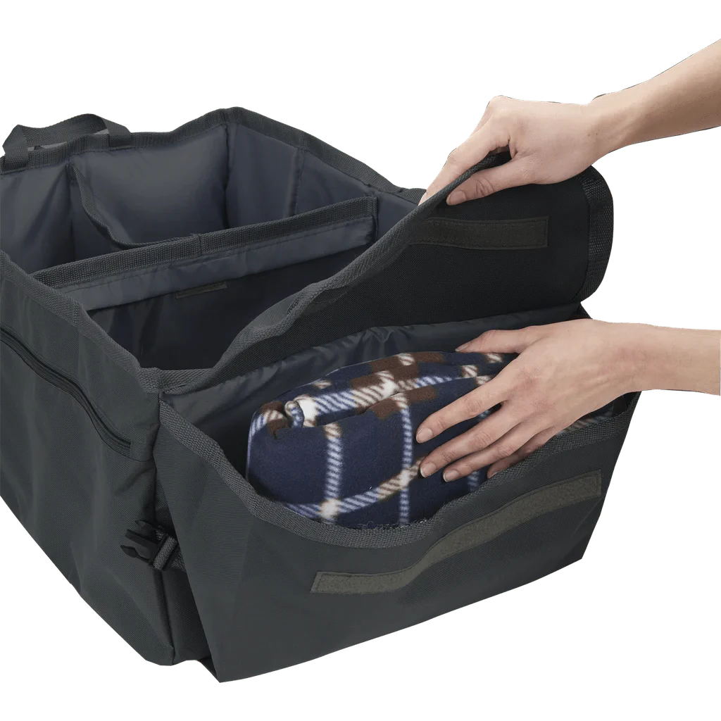 Side angle view of High Road® Trunk & Cargo Organizer, with hands placing blanket inside compartment.