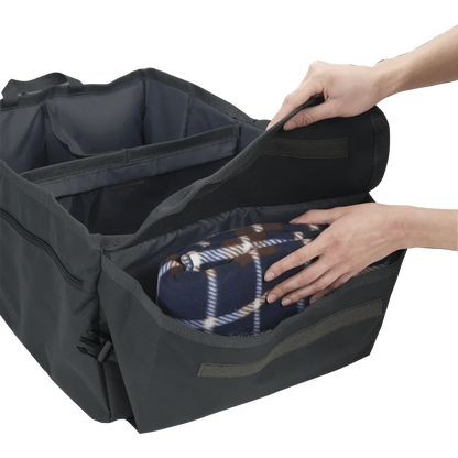 Side angle view of High Road® Trunk & Cargo Organizer, with hands placing blanket inside compartment.