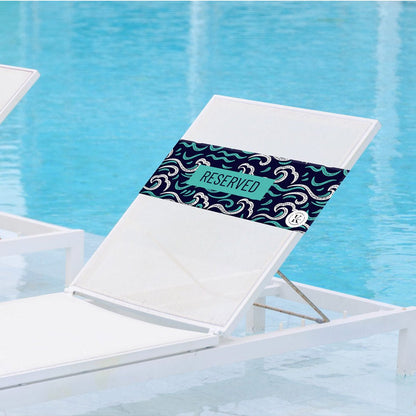 Lifestyle image of ocean K5 Reserved Chair Sleeve, placed on a poolside chair with pool visible in the background.