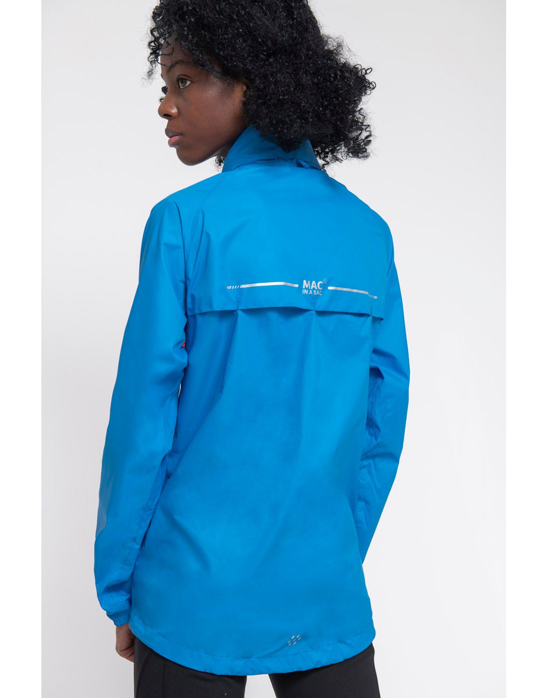 Woman wearing Mac in a Sac Origin II Packable Waterproof Jacket in ocean blue, back view.