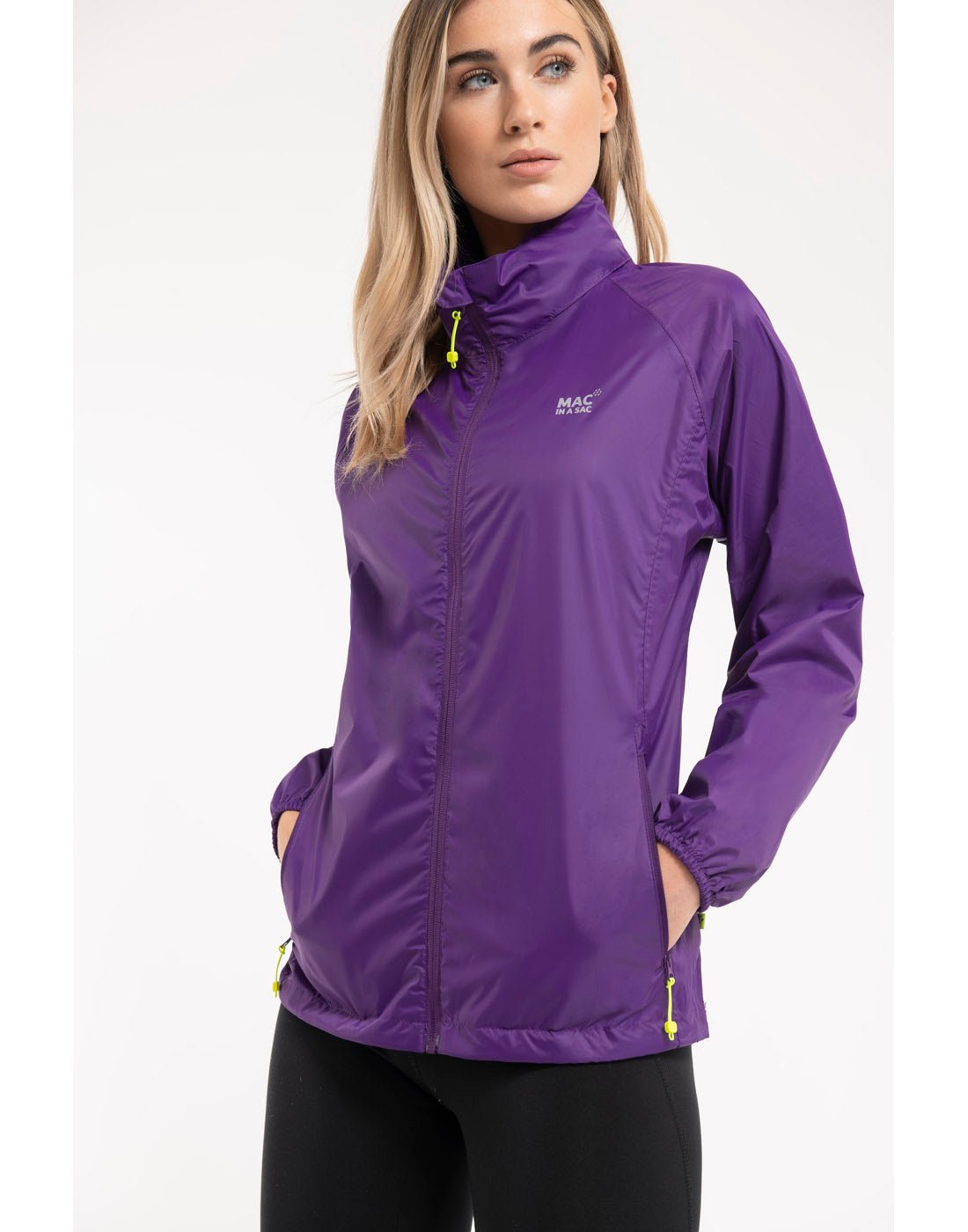 Woman wearing Mac in a Sac Origin II Packable Waterproof Jacket in purple, front view with hands in pockets.