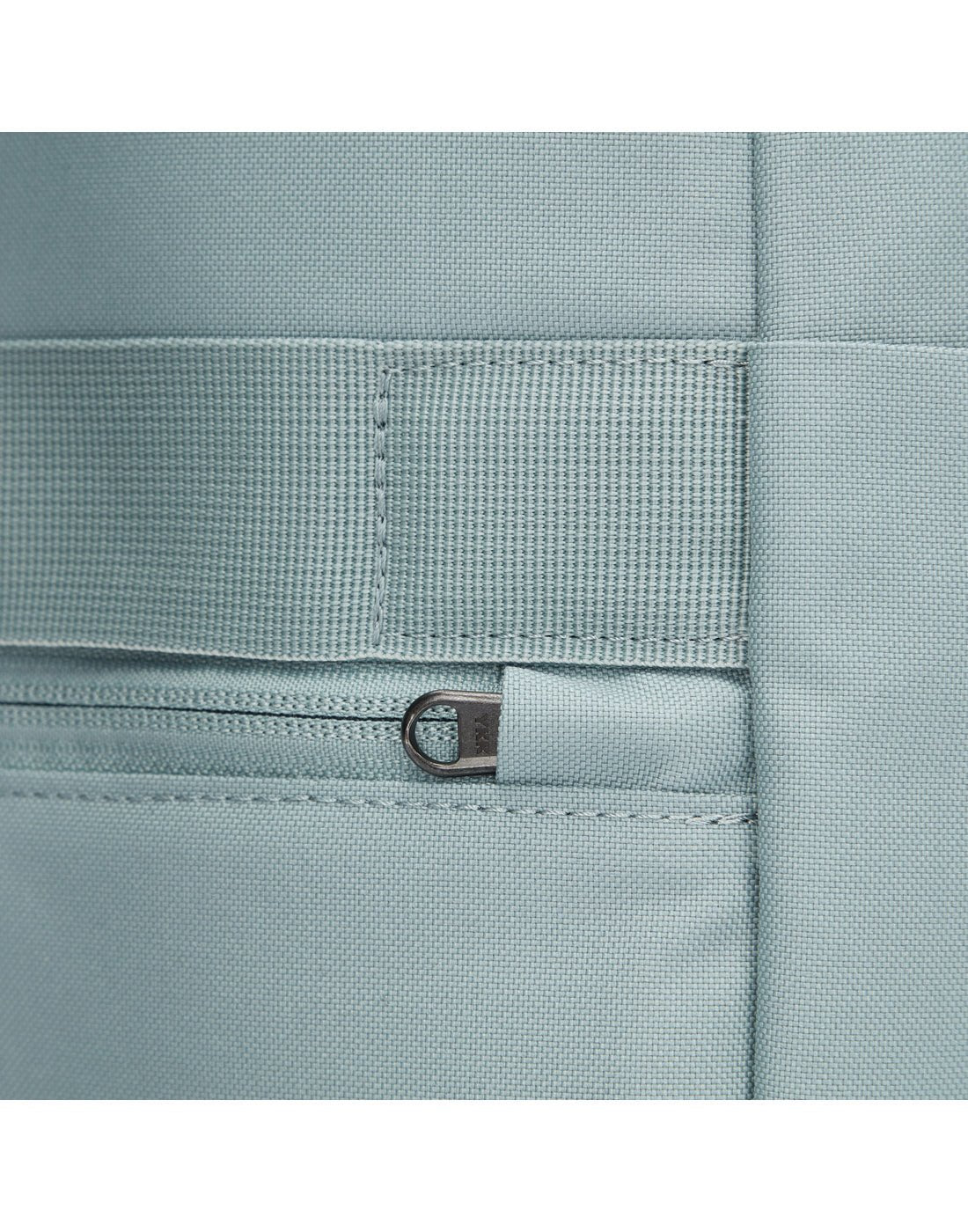 Close up of back zipper pull on fresh mint backpack, tucked into safety slot