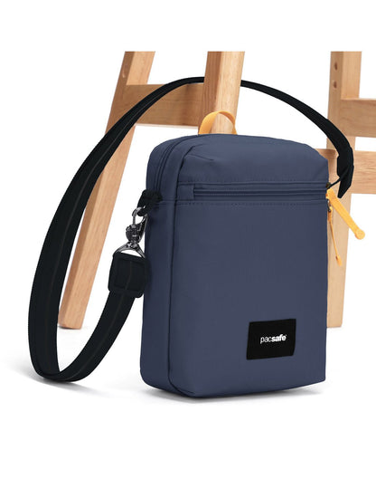 Pacsafe® GO Anti-Theft Festival Crossbody in coastal blue colour with shoulder strap secured to chair leg.