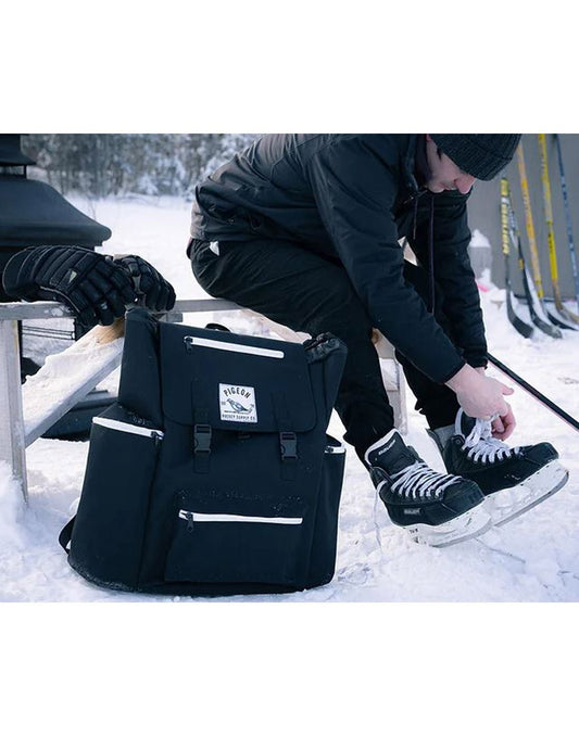 Product Image – Man outdoors in winter sitting on a bench putting on hockey skates with the Pigeon Pack on the snow beside him