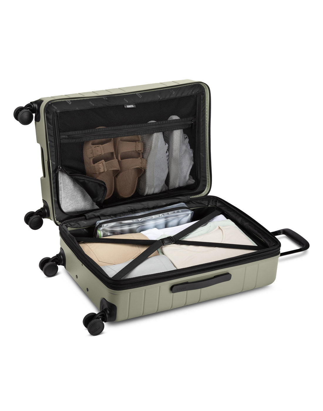 Angled view of unzipped Roots Travel 24" Expandable Hardside Spinner in sage, packed with items.