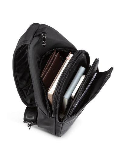 Top view of unzipped Roots Travel Sling Bag in black, with items found inside interior compartments.