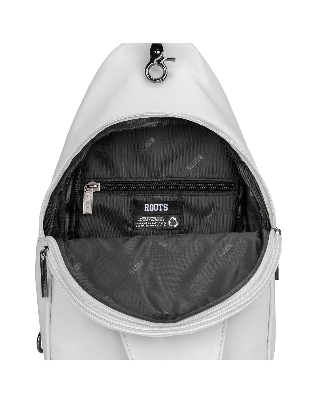 Unzipped Roots Travel Sling Bag in antarctica, close-up view of Roots logo inside first pocket.