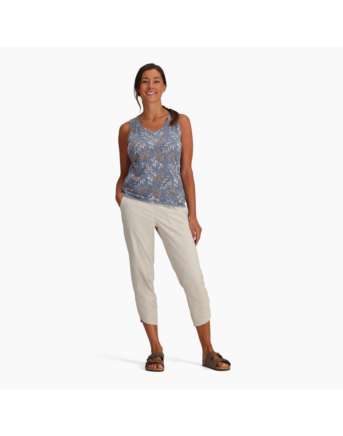 Woman wearing Royal Robbins Women's Featherweight Tank in chicory blue usla print, and khaki pants and sandals, front view with one hand in pocket