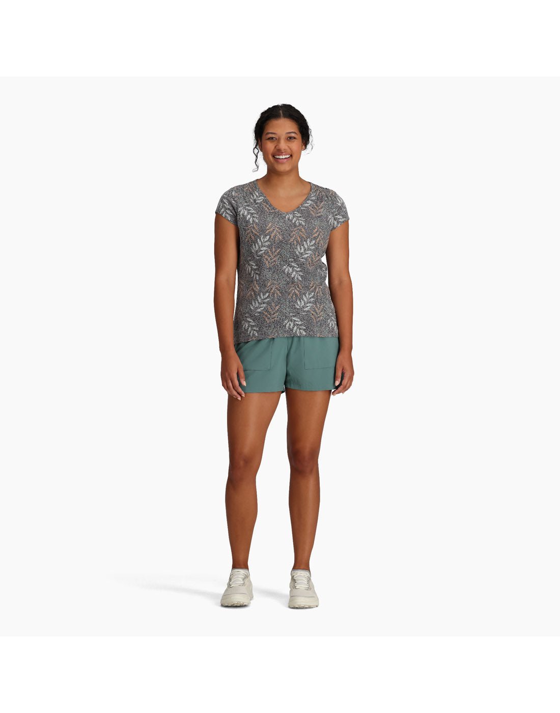 Woman wearing Royal Robbins Women's Featherweight Tee in turbulence usla print with teal shorts and running shoes, front view