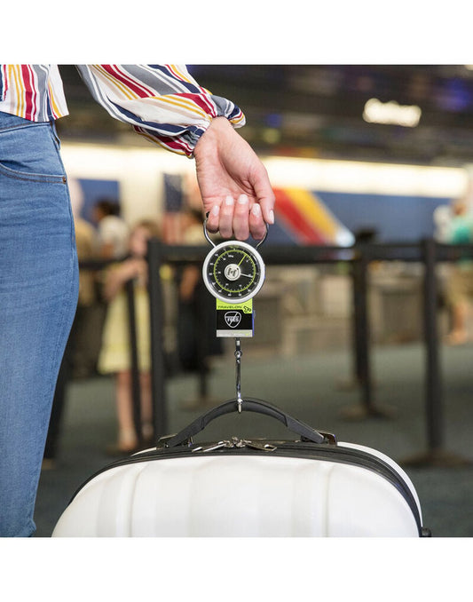 Product Image – Woman holding the Travelon Stop & Lock Luggage Scale with Tape Measure in one hand with a suitcase on the hook