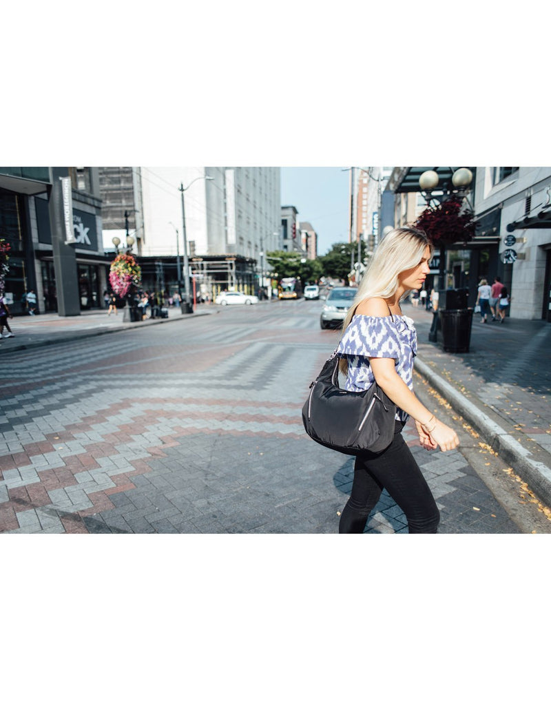 Women carrying pacsafe stylesafe anti-theft convertible black colour crossbody bag side view
