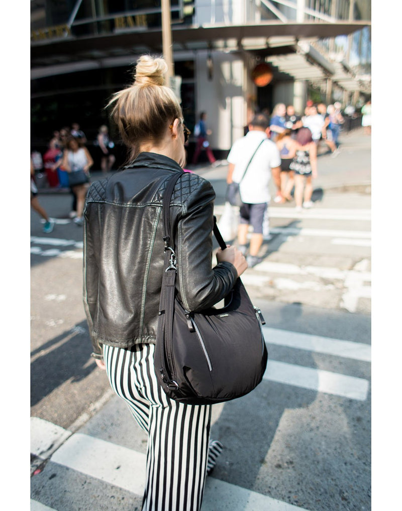 Women carrying pacsafe stylesafe anti-theft convertible black colour crossbody bag corner view