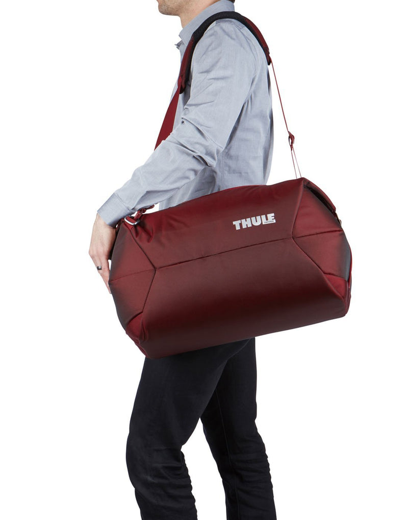 Man using thule subterra 45L ember colour duffel bag 