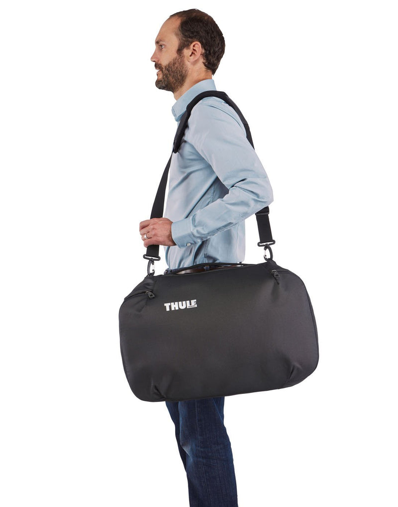 Men using thule subterra carry-on 40L dark shadow colour bag using as shoulder bag side view