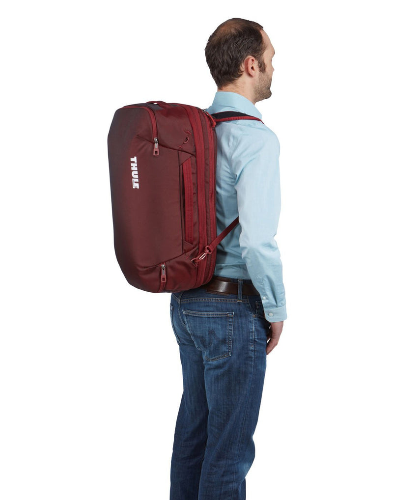 Man with Thule subterra carry-on 40L ember colour bag using as backpack