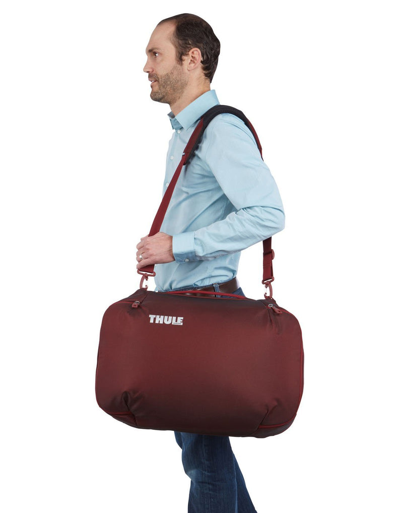 Man with Thule subterra carry-on 40L ember colour bag using as shoulder bag