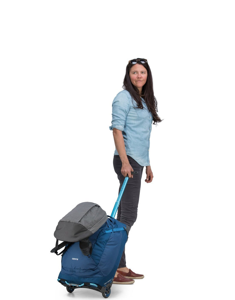 Women carrying osprey ozone 42L/21.5" buoyant blue colour luggage bag tuckaway tow