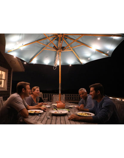 Luci Solar String Lights - lifestyle, on display in backyard attached to a patio umbrella with family eating beneath