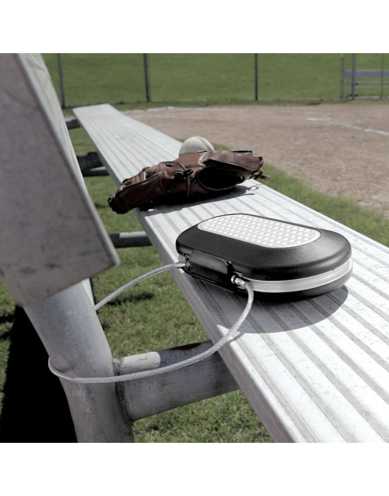 Master Lock® Set-Your-Own-Combination Portable Safe tethered to bleachers with baseball glove and ball beside