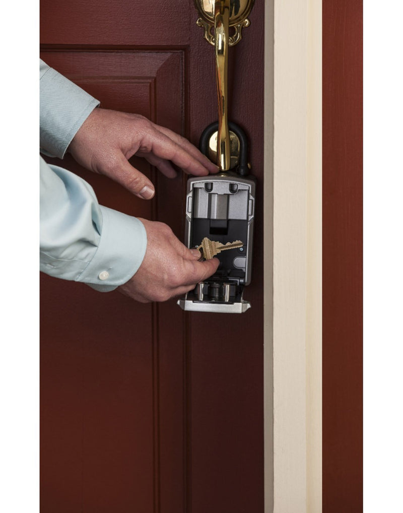 Person's hands retrieving a key from the Master Lock® Bluetooth® Portable Lock Box hung on a door knob