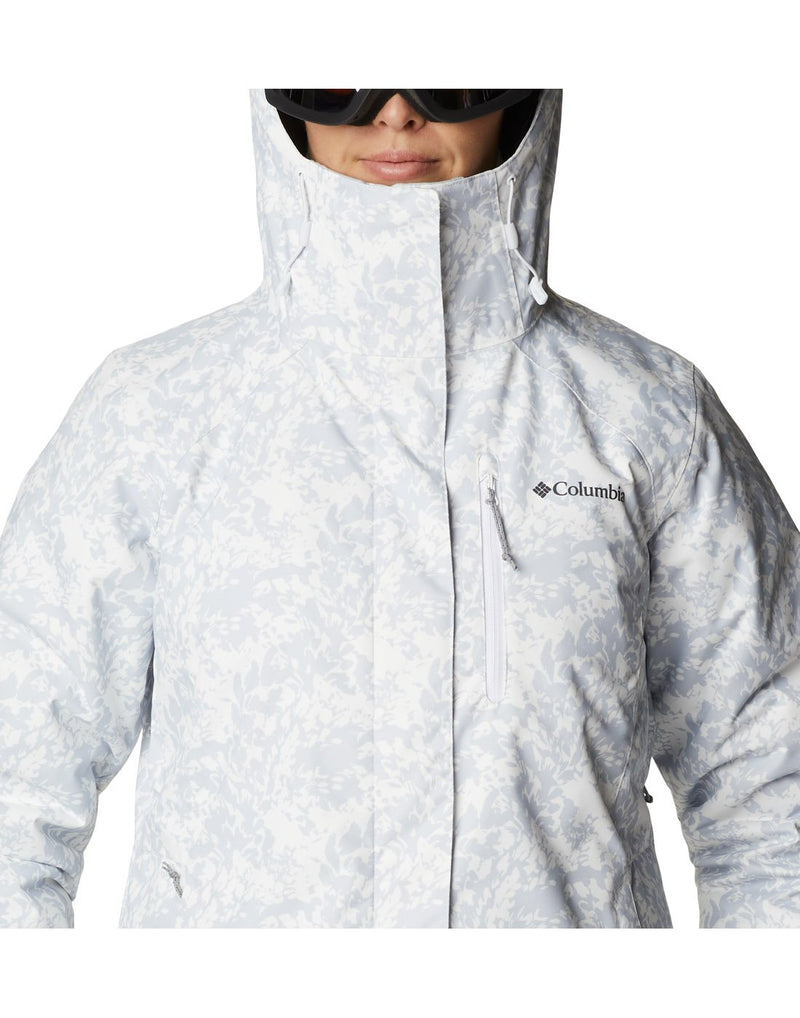 Close up of woman wearing Columbia Women's Whirlibird™ IV Interchange Jacket in white florescence, zipped up and hood up, front view, with Columbia logo and zip pocket on left chest