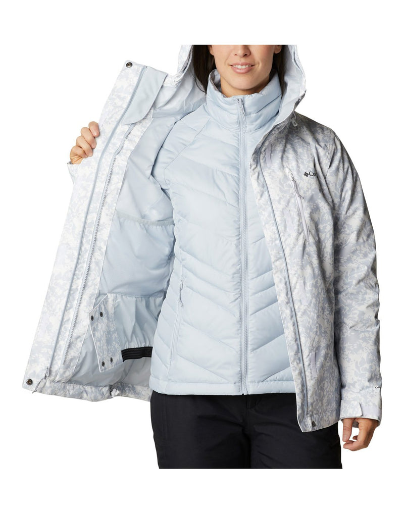 Woman wearing Columbia Women's Whirlibird™ IV Interchange Jacket in white florescence, front view, with top shell unzipped, being held open to show interior