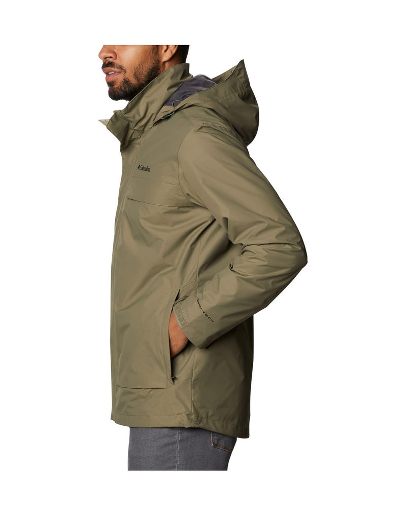 Model wearing Columbia Men's Tryon Trail™ Shell - stone green, side view, zipped up with hands in pockets