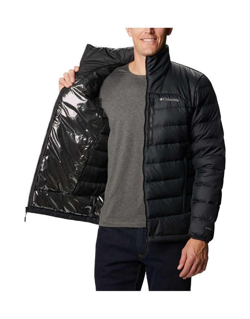 Man wearing Columbia Men's Autumn Park™ Down Jacket in black, unzipped, holding one side open to show reflective lining