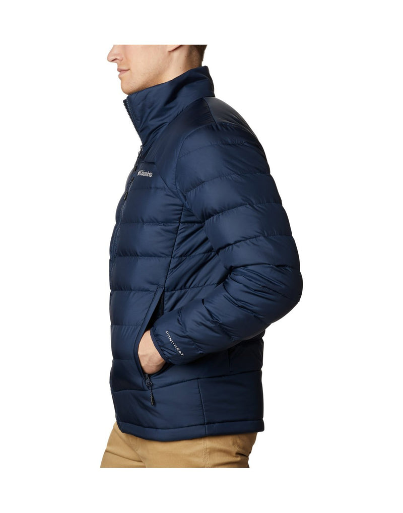 Man wearing Columbia Men's Autumn Park™ Down Jacket in collegiate navy, zipped up, side view with hands in pockets