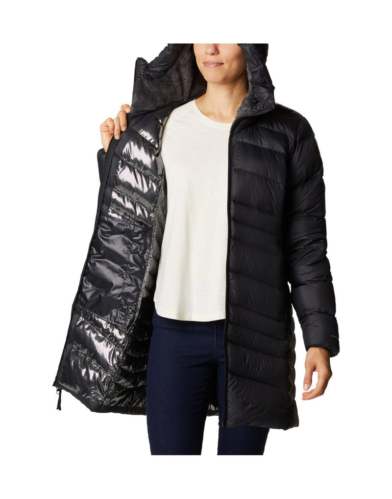 Woman wearing Columbia Women's Autumn Park™ Down Hooded Mid Jacket in black, unzipped, holding one side open to show reflective interior lining, front view