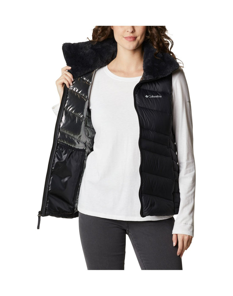 Woman wearing Columbia Women's Autumn Park™ Vest in black, unzipped, front view, holding one side open to show interior lining