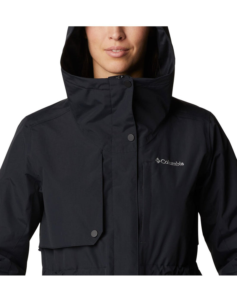 Close up of woman wearing Columbia Women's Hadley Trail™ Jacket in black, zipped up, hood up, front view with Columbia logo on left chest