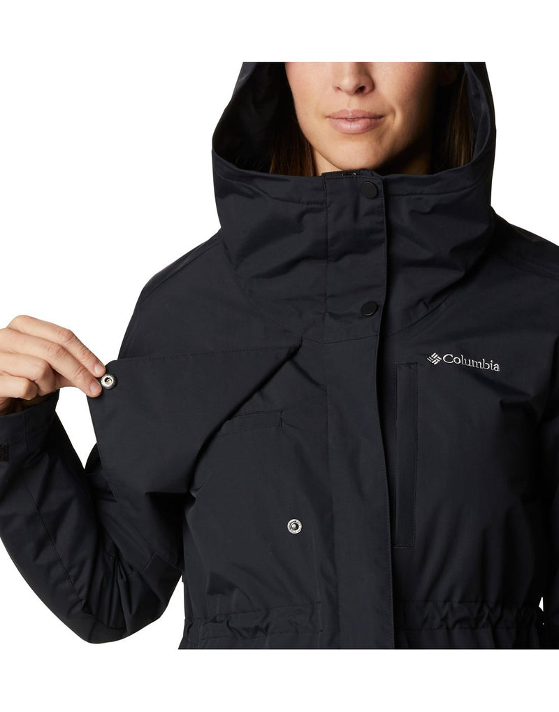 Close up of woman wearing Columbia Women's Hadley Trail™ Jacket in black, zipped up, front view, holding buttoned flap open to show venting