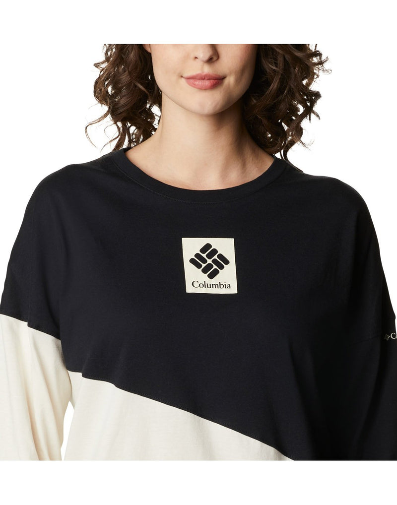 Close up of woman wearing Columbia Women's Columbia Park™ Long Sleeve Tee with black top part and bottom chalk colour and Columbia logo on centre of chest