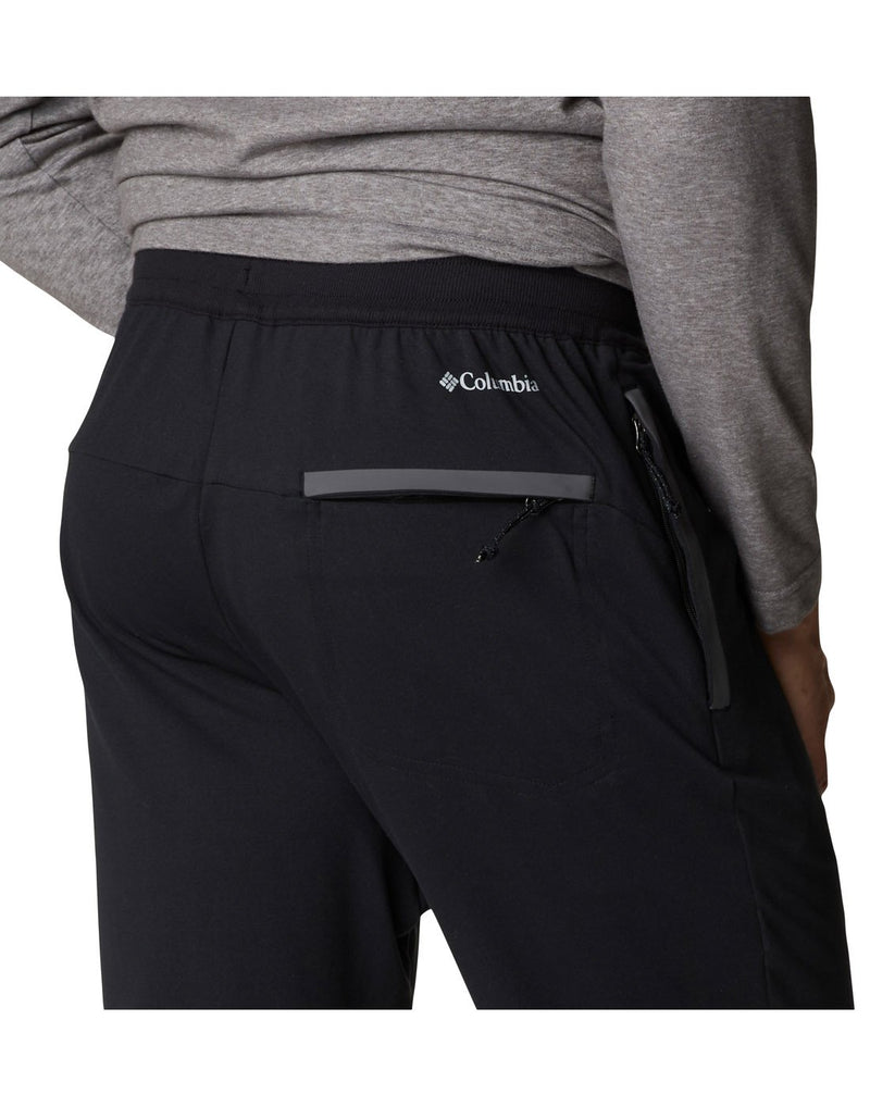 Close up of man wearing Columbia Men's Tech Trail™ Knit Joggers in black, back view showing Columbia logo near waist band and zippered pocket below