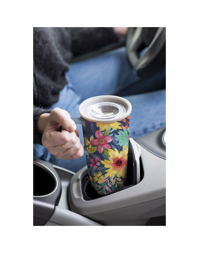 Woman holding the Ceramic FLOMO 360 Travel Cup - 17 oz Summer Garden design, placing it in car cupholder