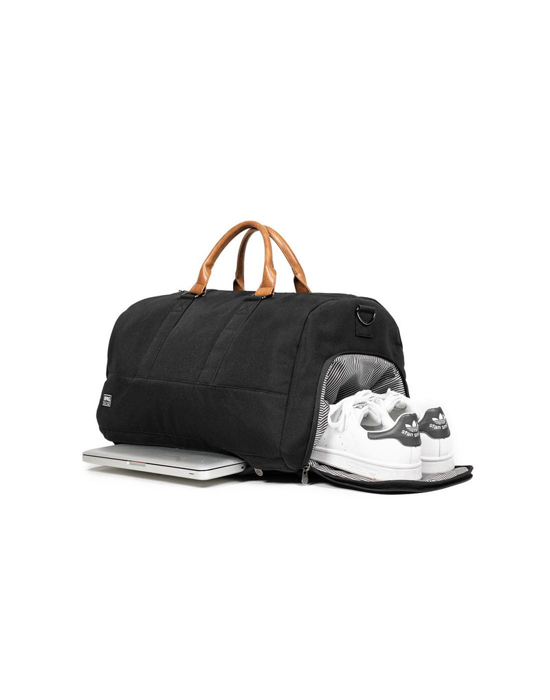 PKG Bishop II Duffle Bag in black with shoe compartment unzipped and shoes half inside and laptop sticking out of bottom zippered compartment