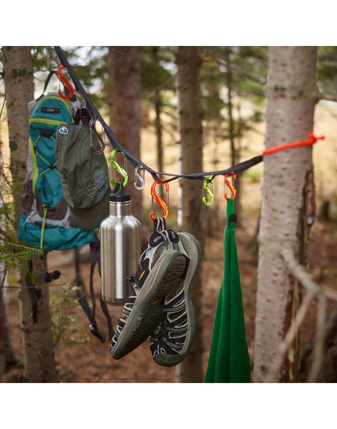 Nite Ize Gearline® Organization System hanging in a forest between two trees with camping gear attached