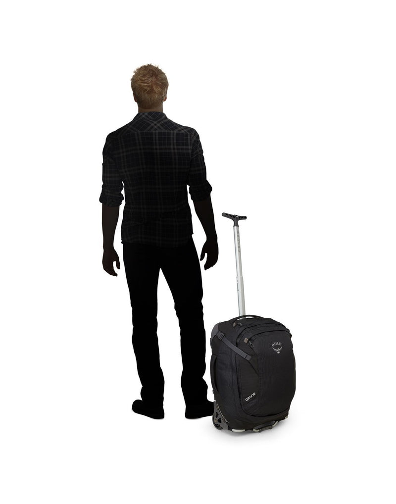 Men standing beside osprey ozone 38L/19.5" global black colour luggage bag body view
