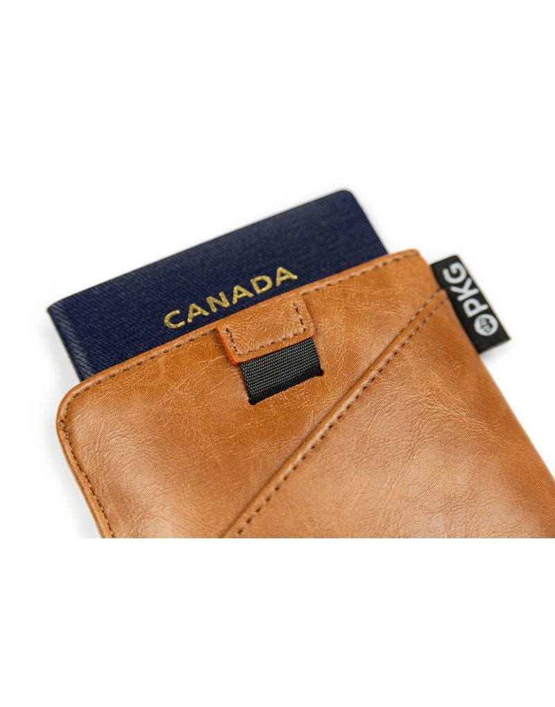 PKG Perry Passport Wallet - tan, close up of back view with pull tab and passport sticking out of top
