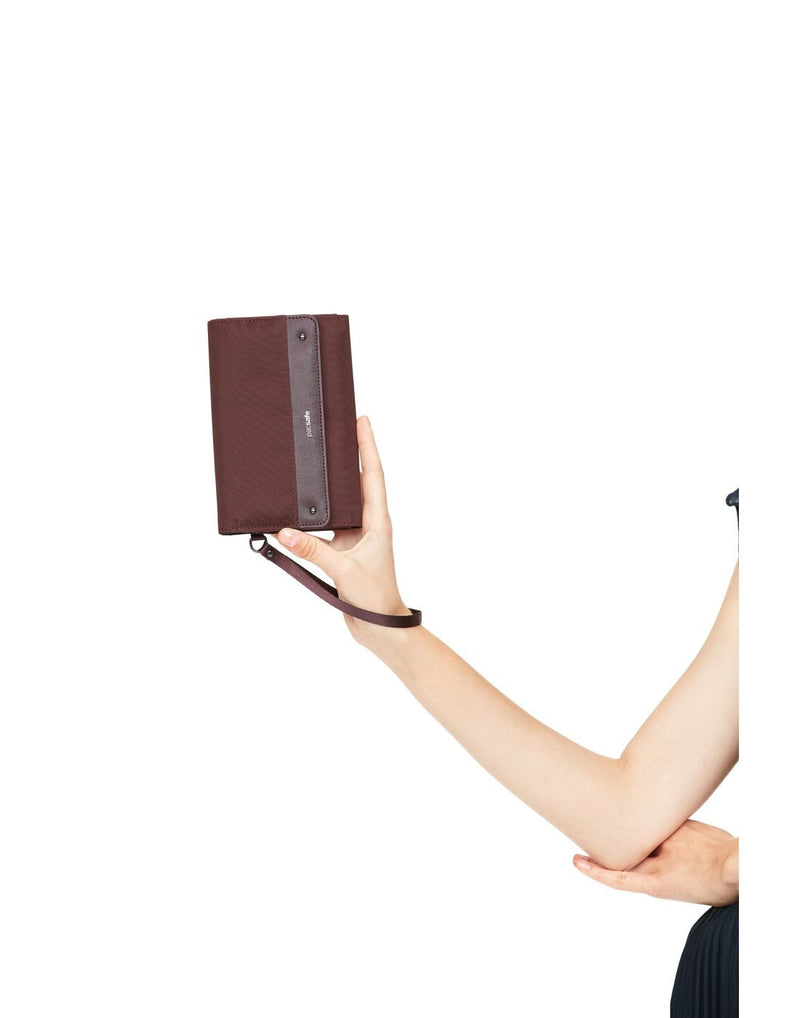 Women holding pacsafe RFID blocking merlot colour clutch wallet front view