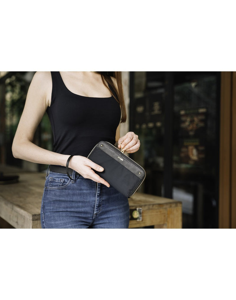 Women carrying pacsafe RFID blocking black colour continental wallet second front view
