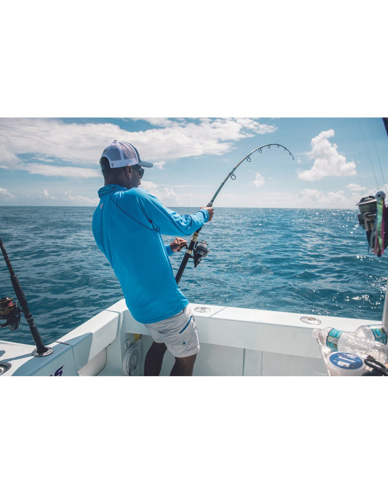 Man fishing off boat wearing beige shorts, mesh cap and Columbia Men's PFG ZERO Rules™ Ice Long Sleeve Shirt in harbor blue