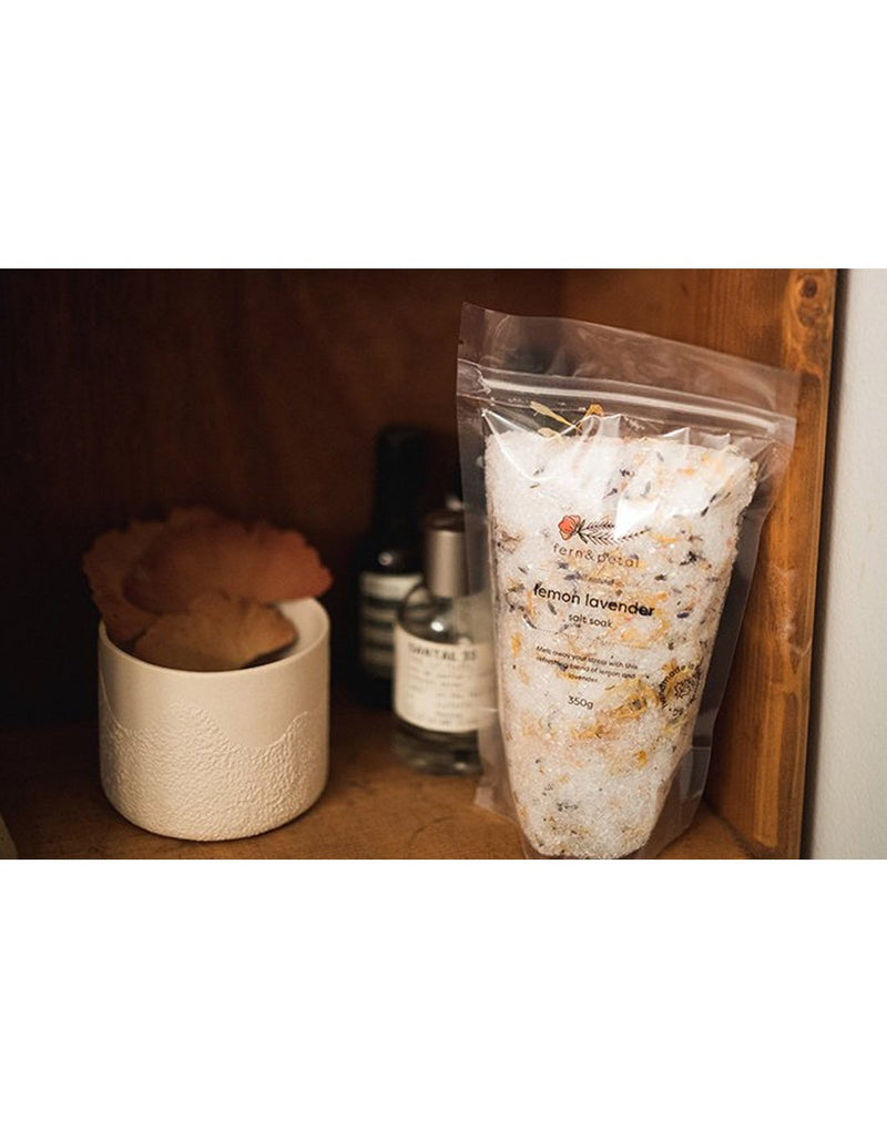 Fern & Petal Lemon Lavender Tea Soak bag sitting on a wooden shelf with various other jars and containers